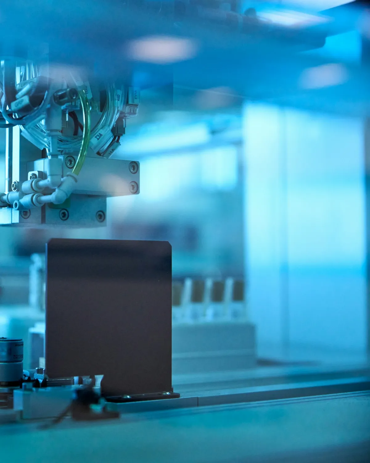 Automated lab machine moving a sample holder under cool blue light
